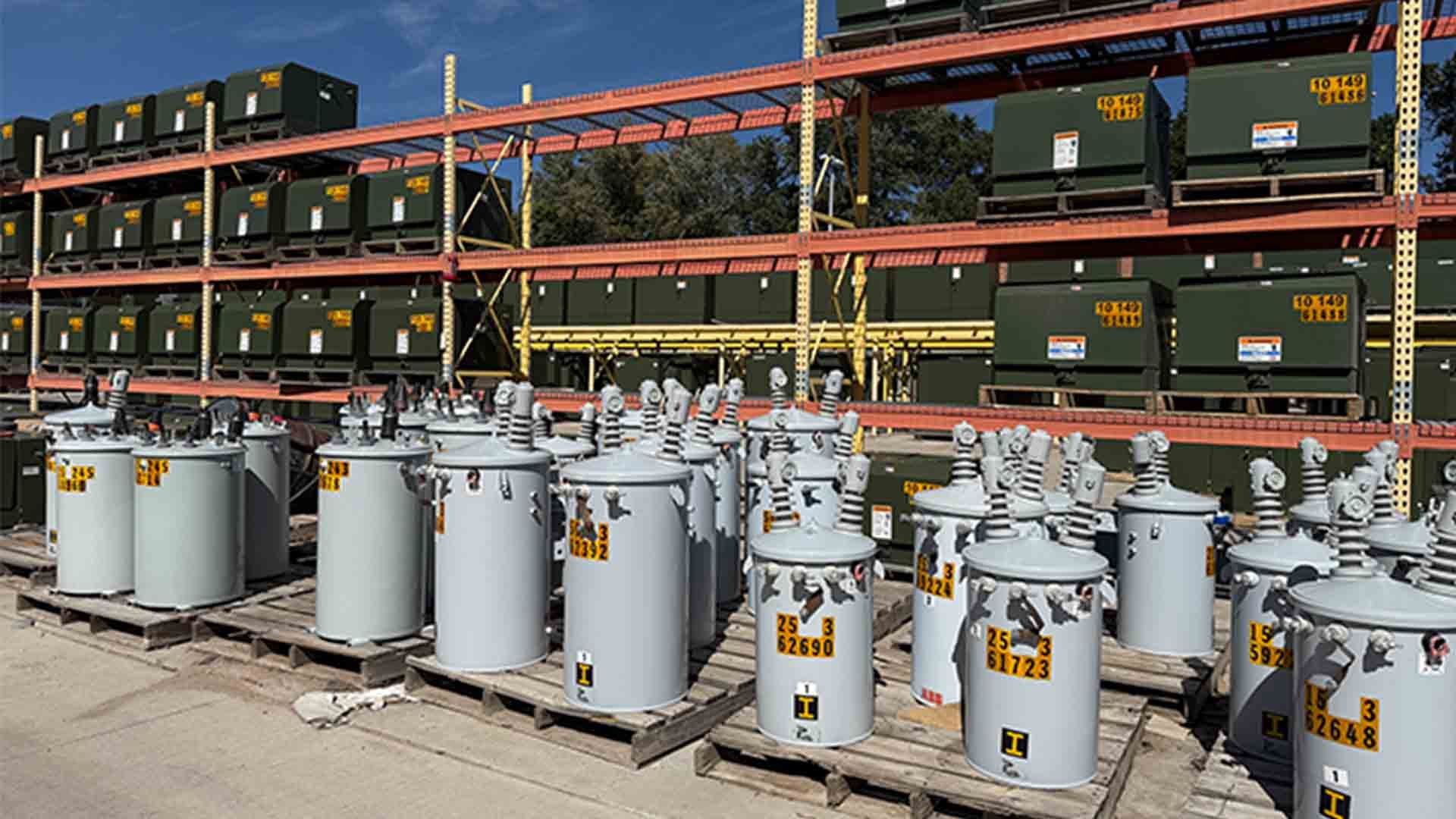 Transformers sit outdoors on shelves and pallets at a Colorado Springs Utilities facility.