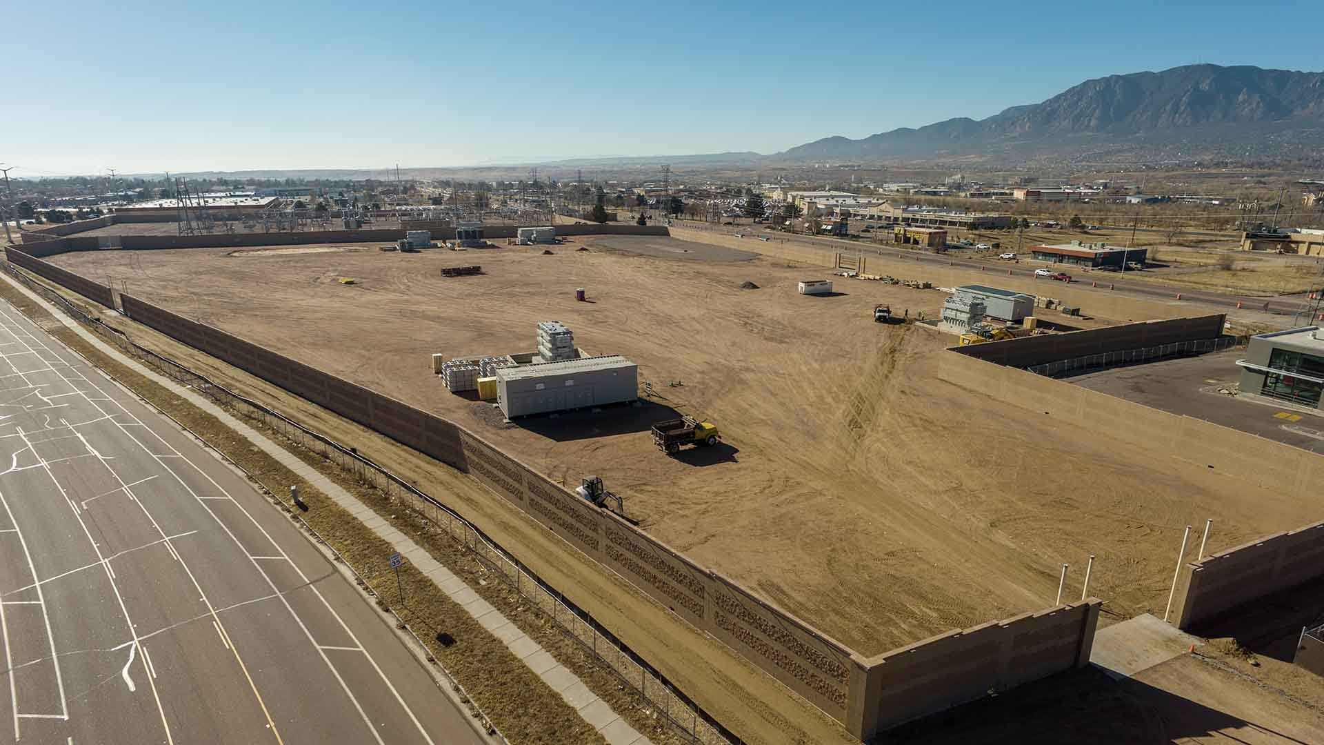 Aerial image of a dirt area inside a wall. The existing Kelker Substation is visible in the far distance, showing the scale of the area.