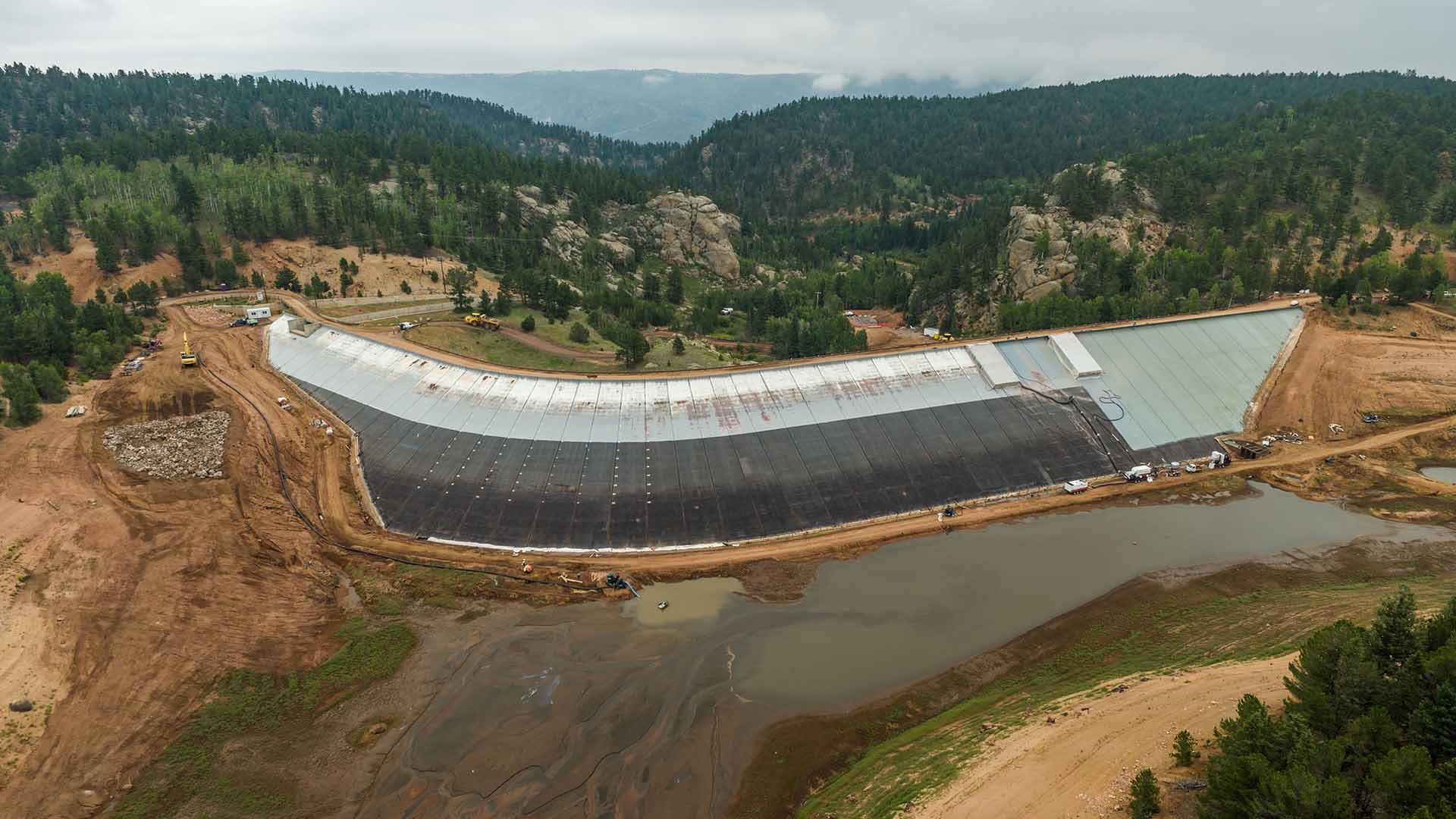 Photo of dam resurfacing work at the drained South Catamount Reservoir on a cloudy day.