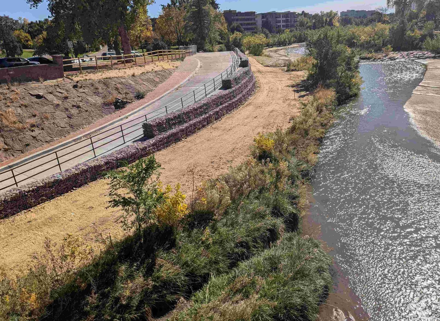 A recently constructed walkway runs parallel to Monument Creek on a sunny day. 