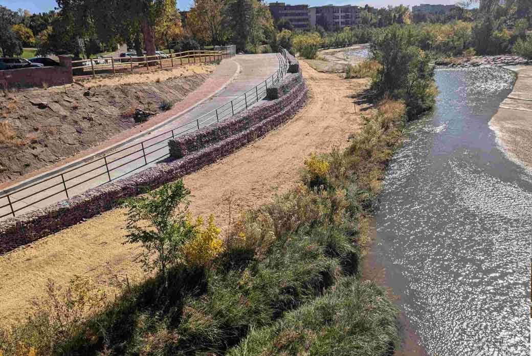 A recently constructed walkway runs parallel to Monument Creek on a sunny day. 