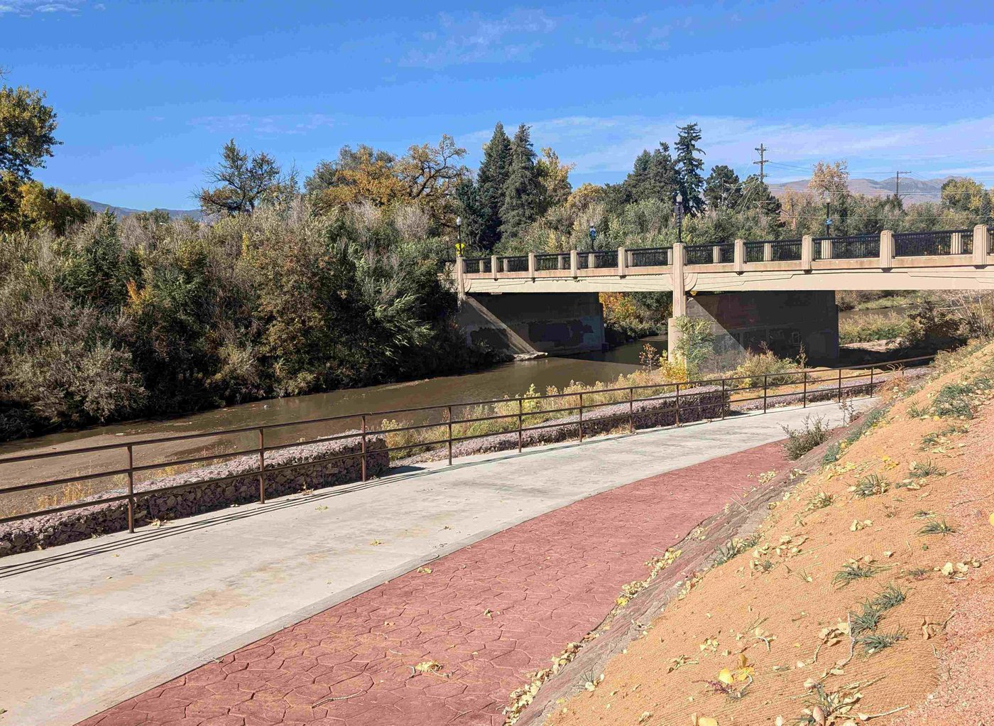 A recently constructed walkway runs parallel to Monument Creek on a sunny day. 