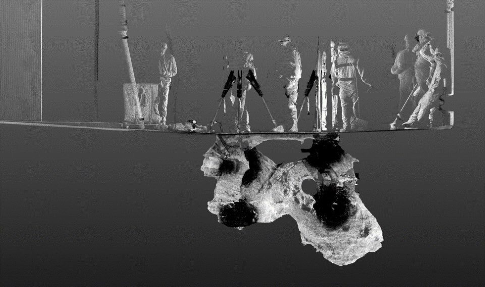 A LiDar scan of a large underground void. Seven workers wearing hardhats appear above ground.