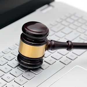 A wooden gavel resting on a laptop keyboard.