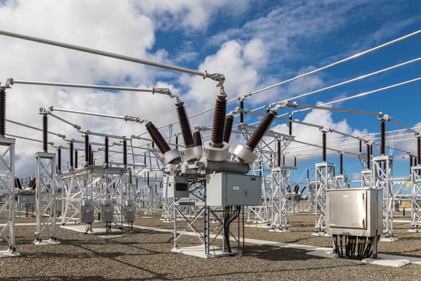 Electrical substation with transformers and power lines under a partly cloudy sky.