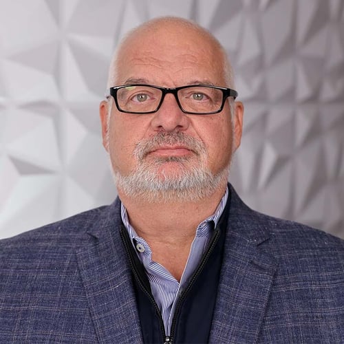 A headshot of a man named Chris Meyers. He is wearing black framed glasses and a blue tweed jacket. 