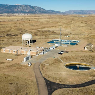 An aerial photograph depicting a water treatment plant in the foothills of the Rocky Mountains.