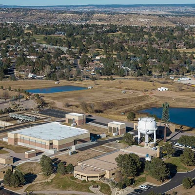 Aerial photo of Tollefson water treatment plant. Two large brick buildings, parking lots, cars, a white water tower, & 2 ponds make up the footprint.