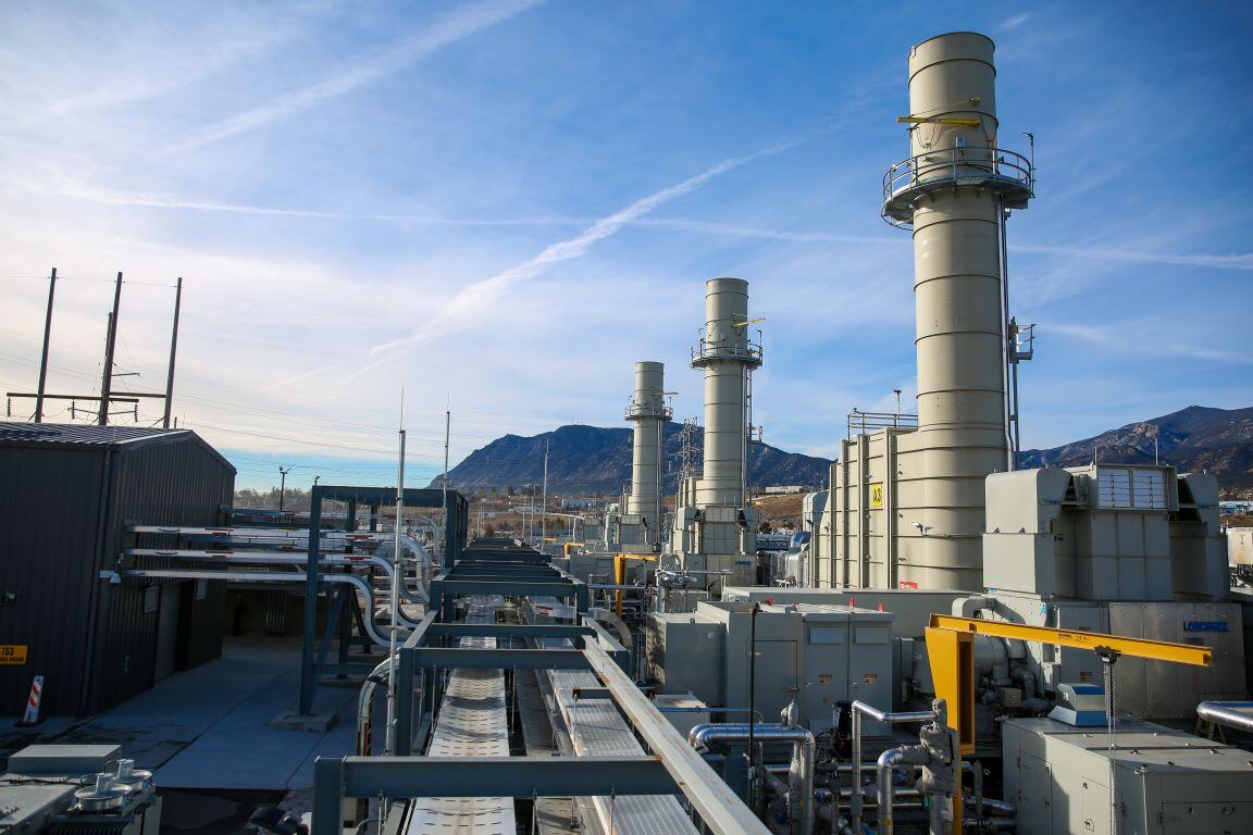 Natural gas generators outside of the Martin Drake Power Plant. There are three smokestacks visible and natural gas piping going to each unit.