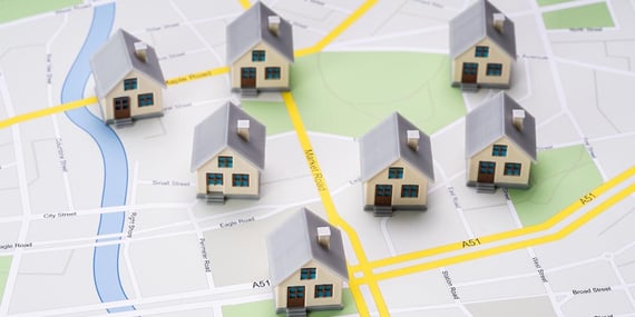 A stock photo of 7 small, three-dimensional house models placed on top of a printed street map.