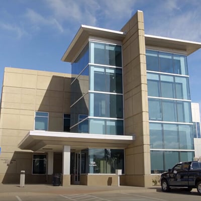 Exterior view of the Colorado Springs Utilities Water Laboratory's two-story building with a prominent glass facade and beige stone.