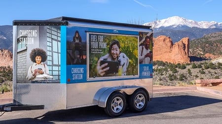 Our charging trailer parked at the Mesa Overlook with Garden of the Gods in the distance. Text on trailer: "Charging station" & "Fuel for your phone"