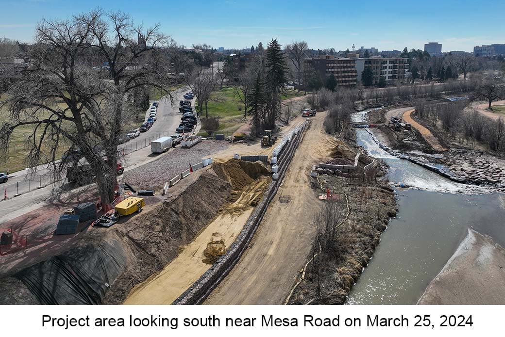 Aerial photo of Monument Creek near Mesa Road on March 25, 2024. A wall is being built between a trail & the creek, water runs in a narrow channel.