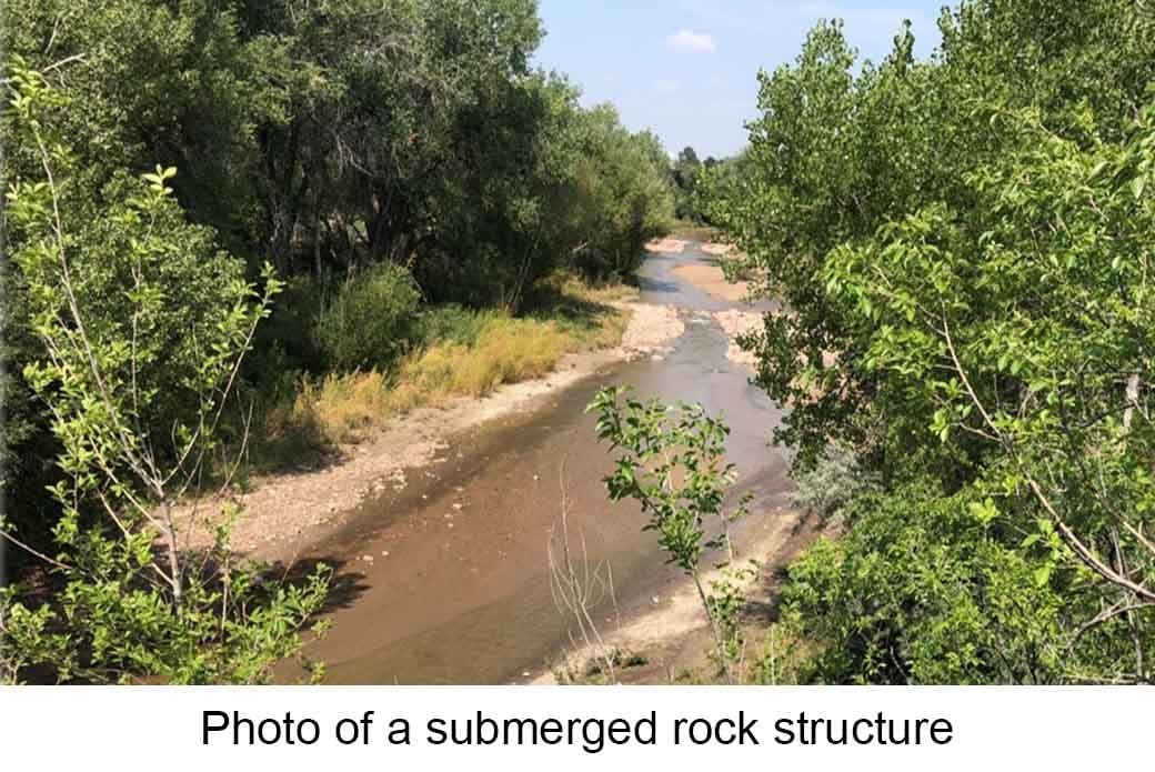 A shallow stream flows over a submerged rock structure. Text reads "Photo of a submerged rock structure"