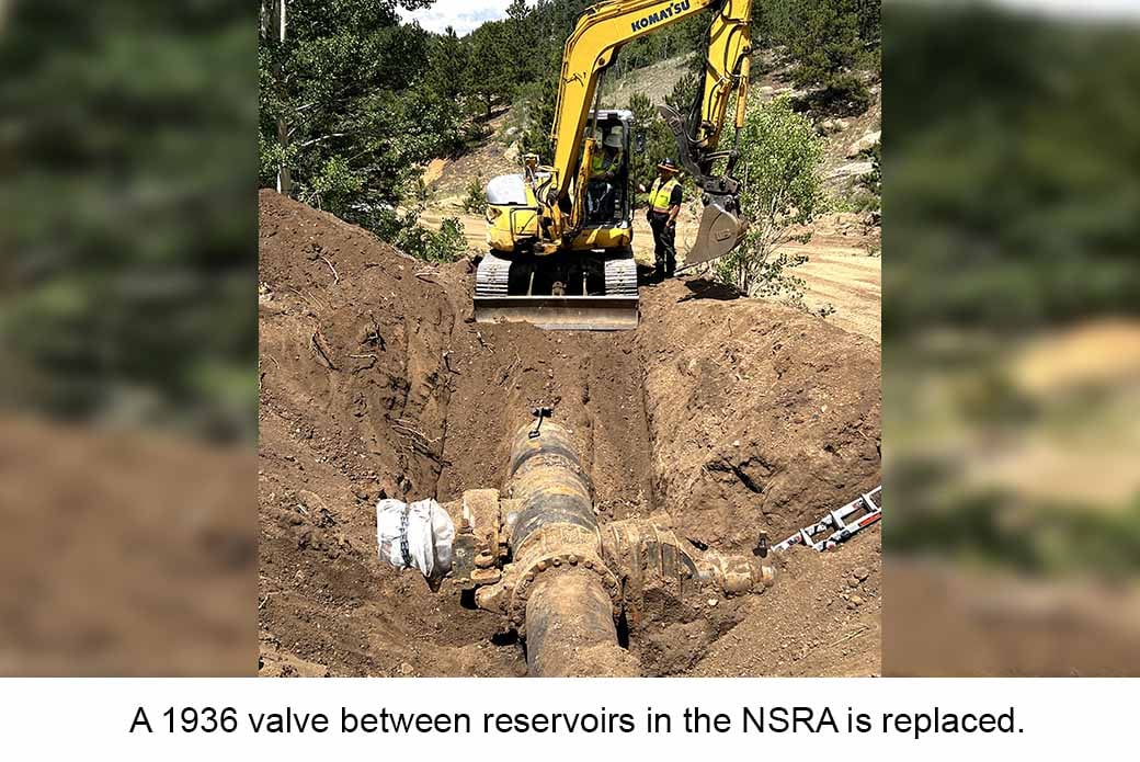 An yellow excavator claws into dirt to replace a 1936 valve between reservoirs in the NSRA.