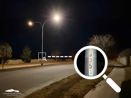 An illuminated streetlight at night. An illustration with a magnifying glass shows the location of the pole number about 3-4 feet above the ground on the pole, showing the streetlight number.