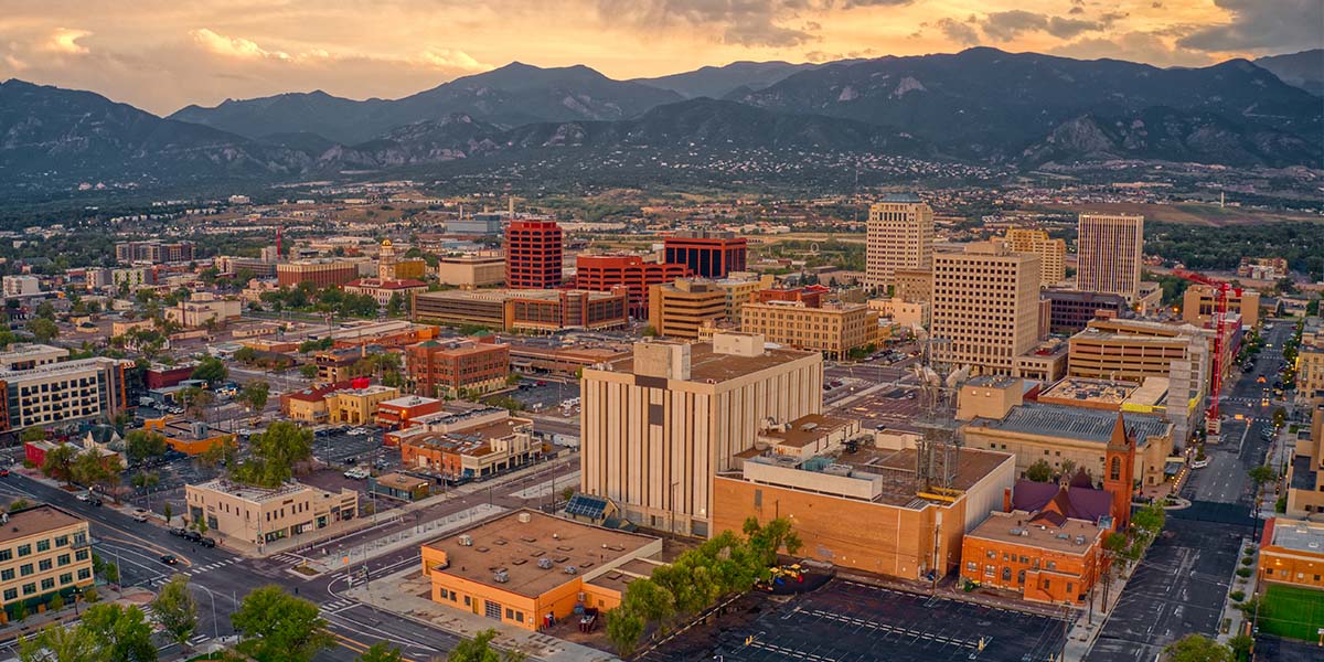 Aerial photo of downtown Colorado Springs at sunset. There is an orange glow in the sky, indicating high clouds or a recent rain.